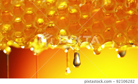 Honey dripping from honey comb on golden background. Honey dripping from honey comb on golden background. 92106282