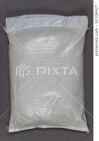 A full white bag against a gray background. Closed bag with food or other products. Top view. Copy space for text and design elements. 92106427