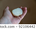 A man holds a peeled onion in his hand. Half of a white raw onion in the hand of a mature man. Selective Focus. 92106442