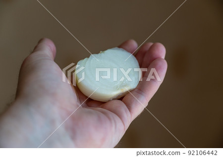 A man holds a peeled onion in his hand. Half of a white raw onion in the hand of a mature man. Selective Focus. A man holds a peeled onion in his hand. Half of a white raw onion in the hand of a mature man. Selective Focus. 92106442