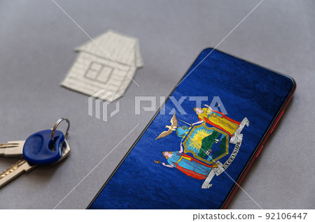 Smartphone, door keys, and paper house on gray background. New York State flag on screen of your device. Buying or renting homes. Moving to live in New York State. Selective Focus. Smartphone, door keys, and paper house on gray background. New York State flag on screen of your device. Buying or renting homes. Moving to live in New York State. Selective Focus. 92106447