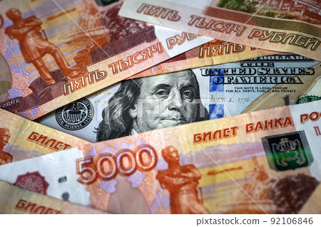 Franklin from US 100 dollar bill watches through Russian ruble banknote pile Franklin from US 100 dollar bill watches through Russian ruble banknote pile 92106846