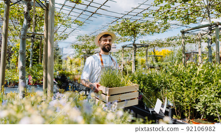 Gardener holding a box of plants. E-commerce, online order concept. Gardener holding a box of plants. E-commerce, online order concept. 92106982