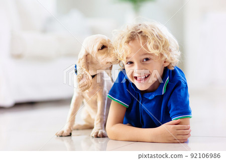 Child playing with dog. Kids play with puppy. 92106986