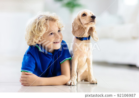 Child playing with dog. Kids play with puppy. 92106987
