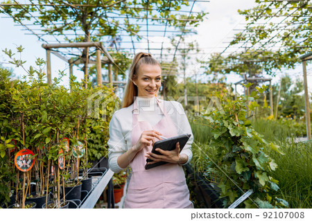 Female florist holding tablet. Owner of garden centre standing a smiling at camera. Female florist holding tablet. Owner of garden centre standing a smiling at camera. 92107008