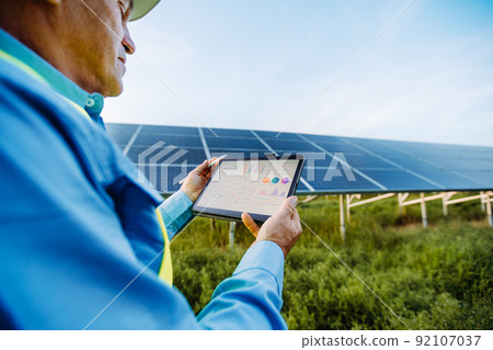 Engineer is holding tablet. Settings of solar system. Alternative energy concept 92107037