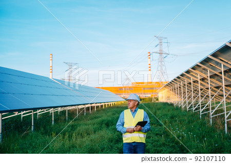 Solar engineer walking in solar farm. Alternative Eco energy concept Solar engineer walking in solar farm. Alternative Eco energy concept 92107110