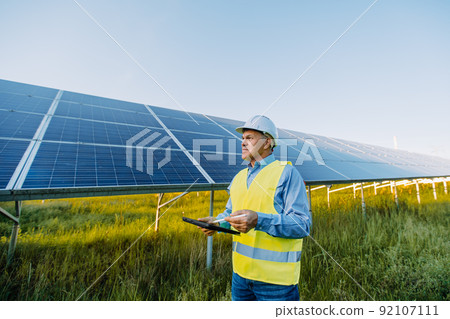 Solar engineer working with digital tablet at renewable energy farm. Alternative Eco energy concept Solar engineer working with digital tablet at renewable energy farm. Alternative Eco energy concept 92107111