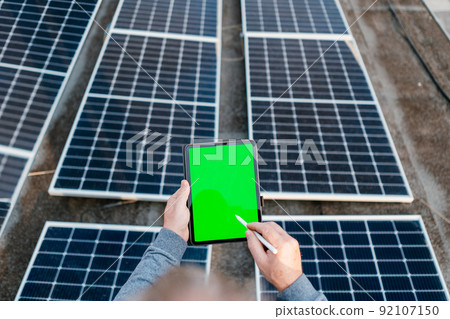 Engineering use a tablet and checking solar power system. Holding tablet with green screen Engineering use a tablet and checking solar power system. Holding tablet with green screen 92107150