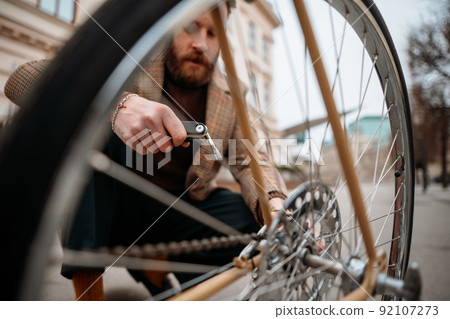 Man checking wheels on bike. Repairing bicycle at street. Man checking wheels on bike. Repairing bicycle at street. 92107273