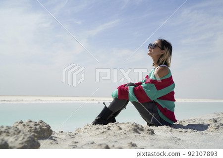 side view of asian woman tourist sitting by a salt lake looking at view 92107893