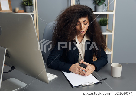 Interested focused tanned adorable curly Latin businesswoman in jacket read tax report on tablet in office interior. Copy space Mockup Banner. Corporation leader lady uses modern computer in work Interested focused tanned adorable curly Latin businesswoman in jacket read tax report on tablet in office interior. Copy space Mockup Banner. Corporation leader lady uses modern computer in work 92109074