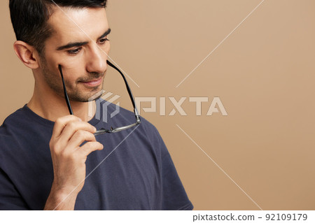 Cheerful man in a gray T-shirt and glasses tin hands isolated background Cheerful man in a gray T-shirt and glasses tin hands isolated background 92109179