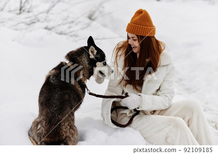 Happy young woman in the snow playing with a dog fun friendship winter holidays 92109185