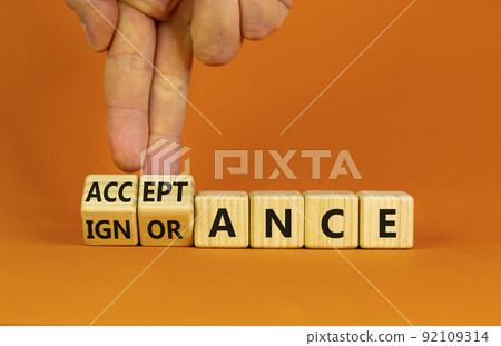 Acceptance or ignorance symbol. Businessman turns cubes, changes the word 'ignorance' to 'acceptance'. Beautiful orange table, orange background. Business, acceptance or ignorance concept. Copy space. 92109314