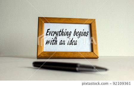 Wooden picture frame with inscription 'everything begins with an idea' on beautiful white background. Pen on the table. Concept. 92109361