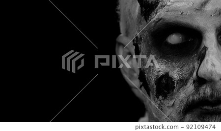 Close-up face of sinister man with horrible scary Halloween zombie makeup looking creepy at camera Close-up face of sinister man with horrible scary Halloween zombie makeup looking creepy at camera 92109474