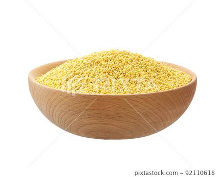 Raw grains of millet in a wooden bowl isolated on white background. 92110618