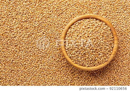 wooden plate with organic wheat on a wheat grains background close-up top view. wooden plate with organic wheat on a wheat grains background close-up top view. 92110656