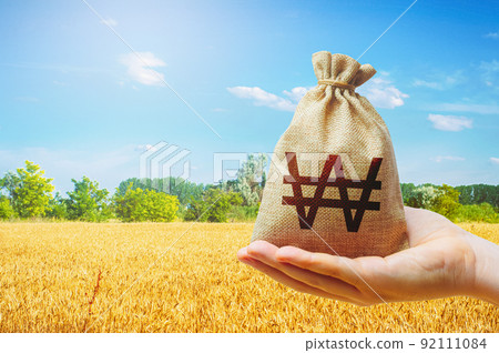Wheat field and south korean won money bag. Food security and fight against hunger. World starvation. Investments in agricultural complex. Profit buy deal. Stock market futures. Agroindustry business. 92111084
