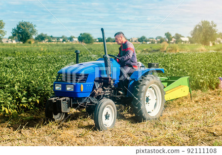 Middle-aged farmer on a tractor. Work on agricultural machinery on the field. Harvest potatoes. Farm and small business. Support and subsidies. Concessional lending and loans. 92111108