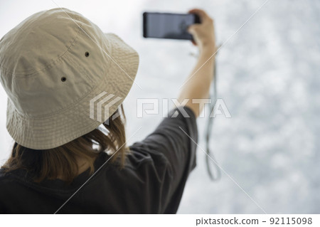 一位年輕女子穿著輕便的衣服在溫暖的房間裡拍攝雪景 一位年輕女子穿著輕便的衣服在溫暖的房間裡拍攝雪景 92115098