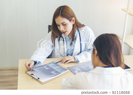 Two asian women doctors discuss meeting doctor's office medical clinic using laptop consulting patient disease. Asian medical lab young women talking together discussing healthcare assistance teamwork Two asian women doctors discuss meeting doctor's office medical clinic using laptop consulting patient disease. Asian medical lab young women talking together discussing healthcare assistance teamwork 92118088
