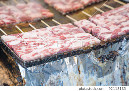 Grilled square beef sticks (Japanese) are arranged on the big pan plate with smoke around. 92118183