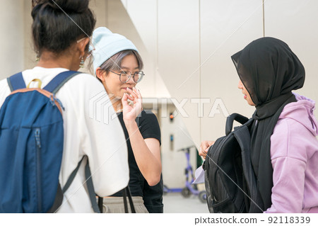 Happy Asian college students standing and talking Happy Asian college students standing and talking 92118339