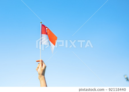 hand holding Singapore flag on blue sky background. Singapore National Day and happy celebration concepts hand holding Singapore flag on blue sky background. Singapore National Day and happy celebration concepts 92118440