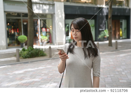 一個在人行道上停下來操作智能手機的女人 92118706