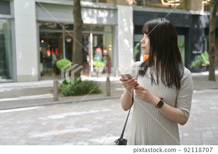 一個在人行道上停下來操作智能手機的女人 92118707