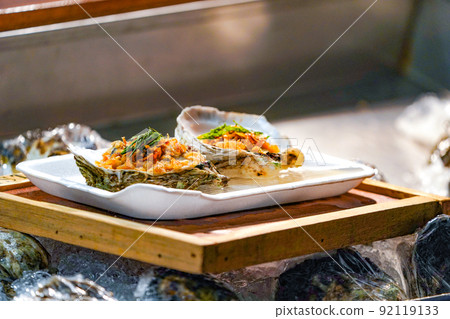 Fresh Raw big couple Oysters on the foam dish and wooden plate topping by fried garlic and leaf the ready to serve. 92119133
