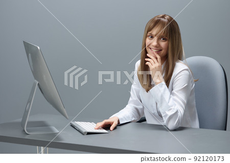 Cute pretty blonde businesswoman freelancer using computer chatting with clients look at camera in gray modern office of support service. Remote Job, Technology Career Profession Concept. Copy space Cute pretty blonde businesswoman freelancer using computer chatting with clients look at camera in gray modern office of support service. Remote Job, Technology Career Profession Concept. Copy space 92120173