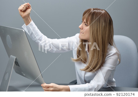 Angry evil pretty blonde businesswoman worker screaming to desktop Raging after computer software crash error sitting at workplace in gray modern office. Technology Gadget Crash Concept. Copy space 92120174
