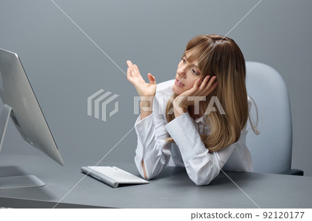 Bored pretty blonde businesswoman worker freelancer using desktop computer sitting at workplace in gray modern office. Remote Job, Technology And Career Profession Concept. Copy space Bored pretty blonde businesswoman worker freelancer using desktop computer sitting at workplace in gray modern office. Remote Job, Technology And Career Profession Concept. Copy space 92120177