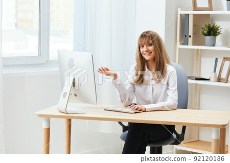 Smiling cheerful adorable blonde businesswoman worker freelancer look at camera raise hand up in light modern office. Happy employee work on computer online, enjoy successful business. Copy space Smiling cheerful adorable blonde businesswoman worker freelancer look at camera raise hand up in light modern office. Happy employee work on computer online, enjoy successful business. Copy space 92120186