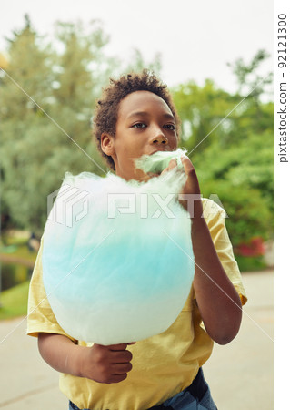 Boy eating cotton candy outdoors 92121300