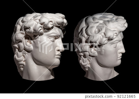 Two gypsum copy of head statue David for artists on a dark background. Replica of face famous antique sculpture youth of David by Michelangelo. Template design for art, dj, fashion, poster. Profile. 92121665