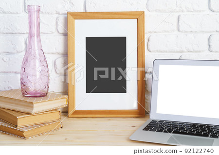 Blank picture frame on wooden table with books and laptop Blank picture frame on wooden table with books and laptop 92122740