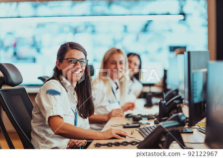 Group of female security operators working in a data system control room Technical Operators Working at workstation with multiple displays, security guards working on multiple monitors in surveillan 92122967
