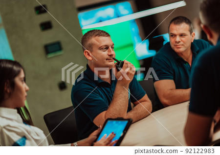 Group of security guards sitting and having briefing In the system control room They're working in security data center surrounded by multiple Screens Group of security guards sitting and having briefing In the system control room They're working in security data center surrounded by multiple Screens 92122983