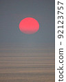 The sun is falling into the sea and being partially swallowed by the fog.  sky  is dark 92123757