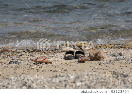 Travelers take off casual shoes on the beach by the sea to swim. 92123764