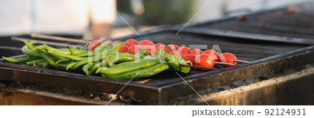 Amateur chef going to fry fresh tomatoes and green pepper on grill in nature Amateur chef going to fry fresh tomatoes and green pepper on grill in nature 92124931