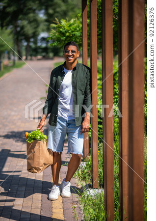 Man standing with food bag looking at camera Man standing with food bag looking at camera 92126376