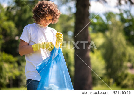 Young volunteer with bags full of [plastic garbage 92126546