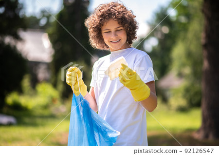Young volunteer with bags full of [plastic garbage 92126547