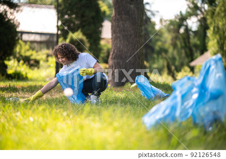 Kid in white tshirt gathering plastic litter in the park Kid in white tshirt gathering plastic litter in the park 92126548